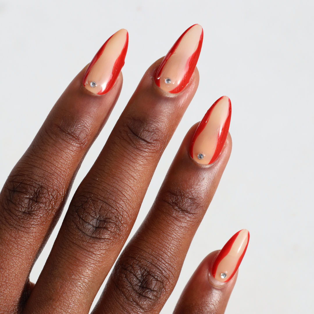 Angled photo of dark skinned hand with Red Accent with Gems Nails