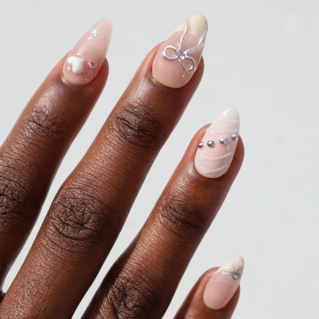 Angled photo of dark skinned hand with Bow and Charms Chrome Nails