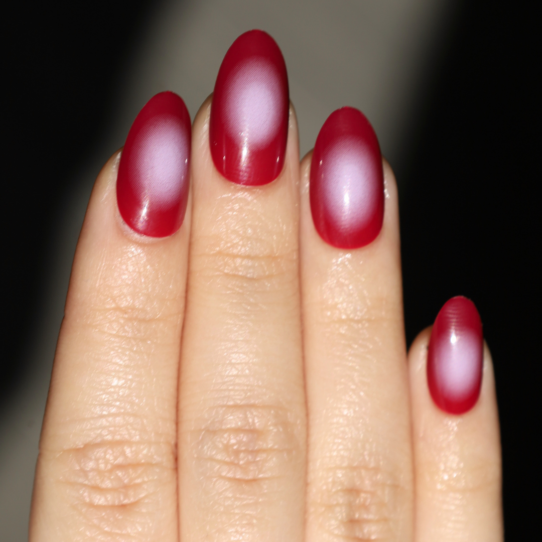Light skinned hand with red and white aura nails