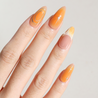 Angled photo of light skinned hand with Orange Chrome Moderne Nails
