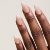 Angled photo of dark skinned hand with Pearl Nude French Tip Nails