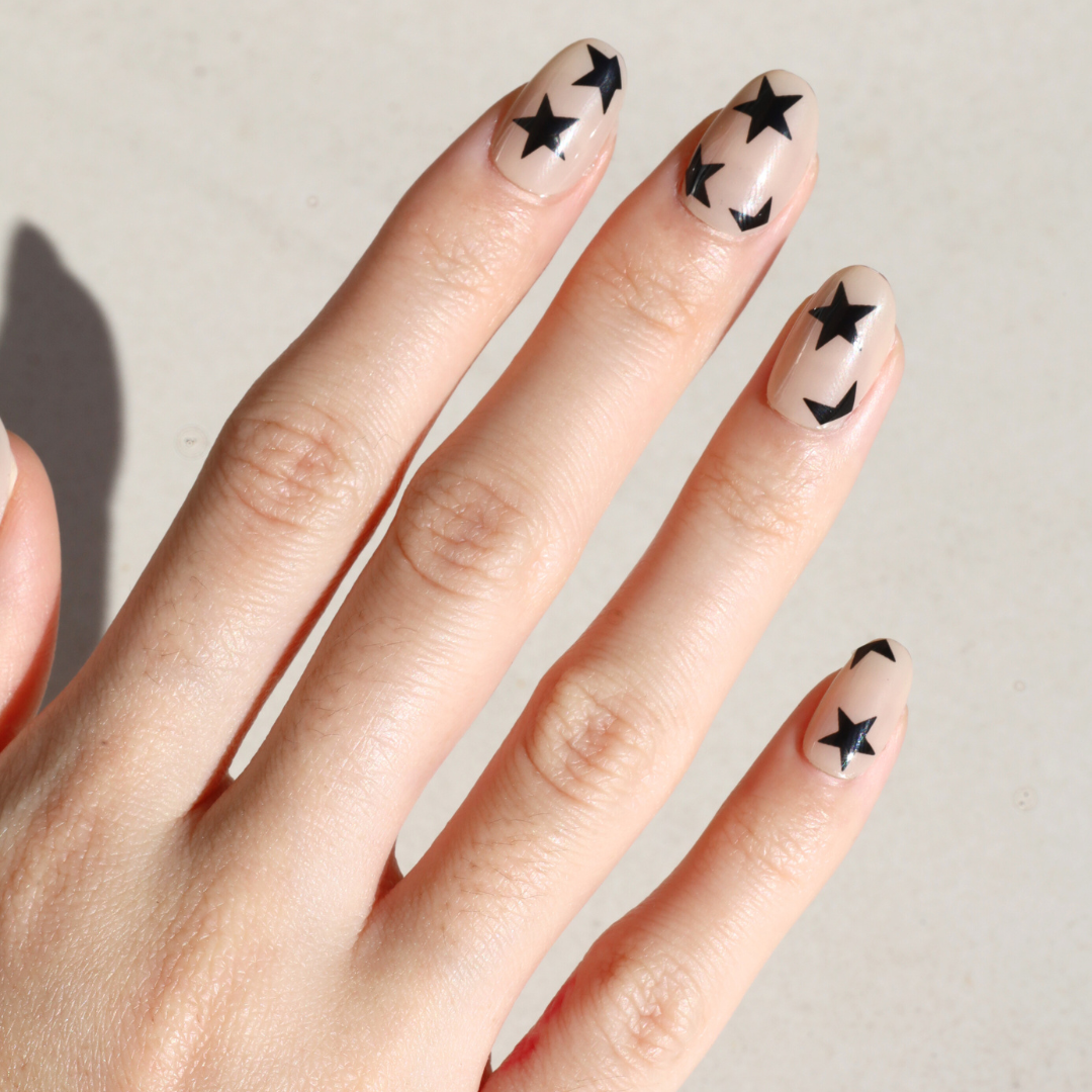 Angled photo of light skinned hand with Black Star Nails