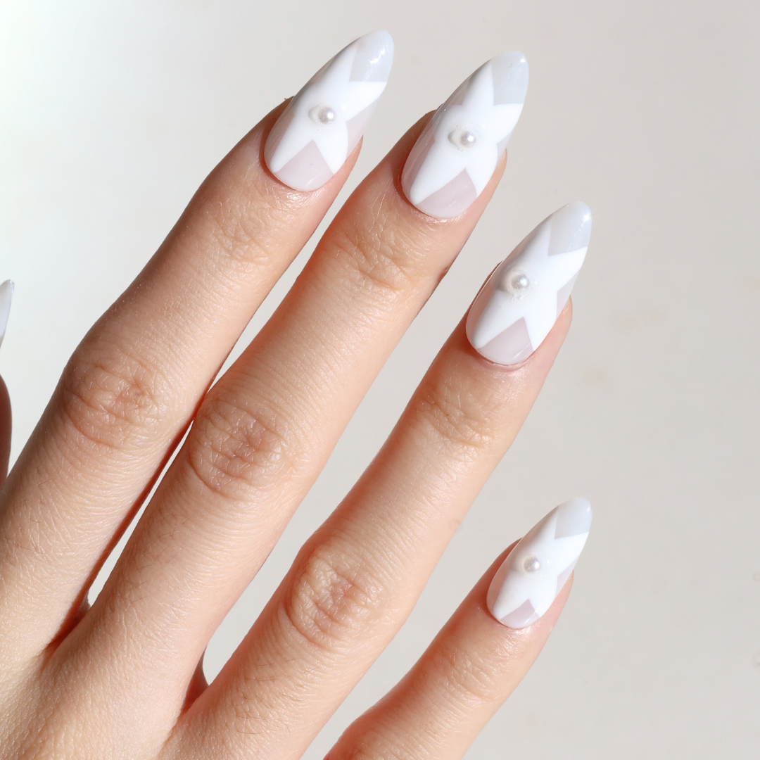 Angled photo of light skinned hand with Winter White Star Pearl Nails