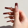 Light skinned thumb with Cherry 3D Bow Coffin Nails