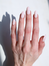 Long almond glossy nude press on nails close up on light toned hand