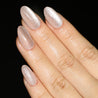 Angled photo of light skinned hand with pink cat-eye nails