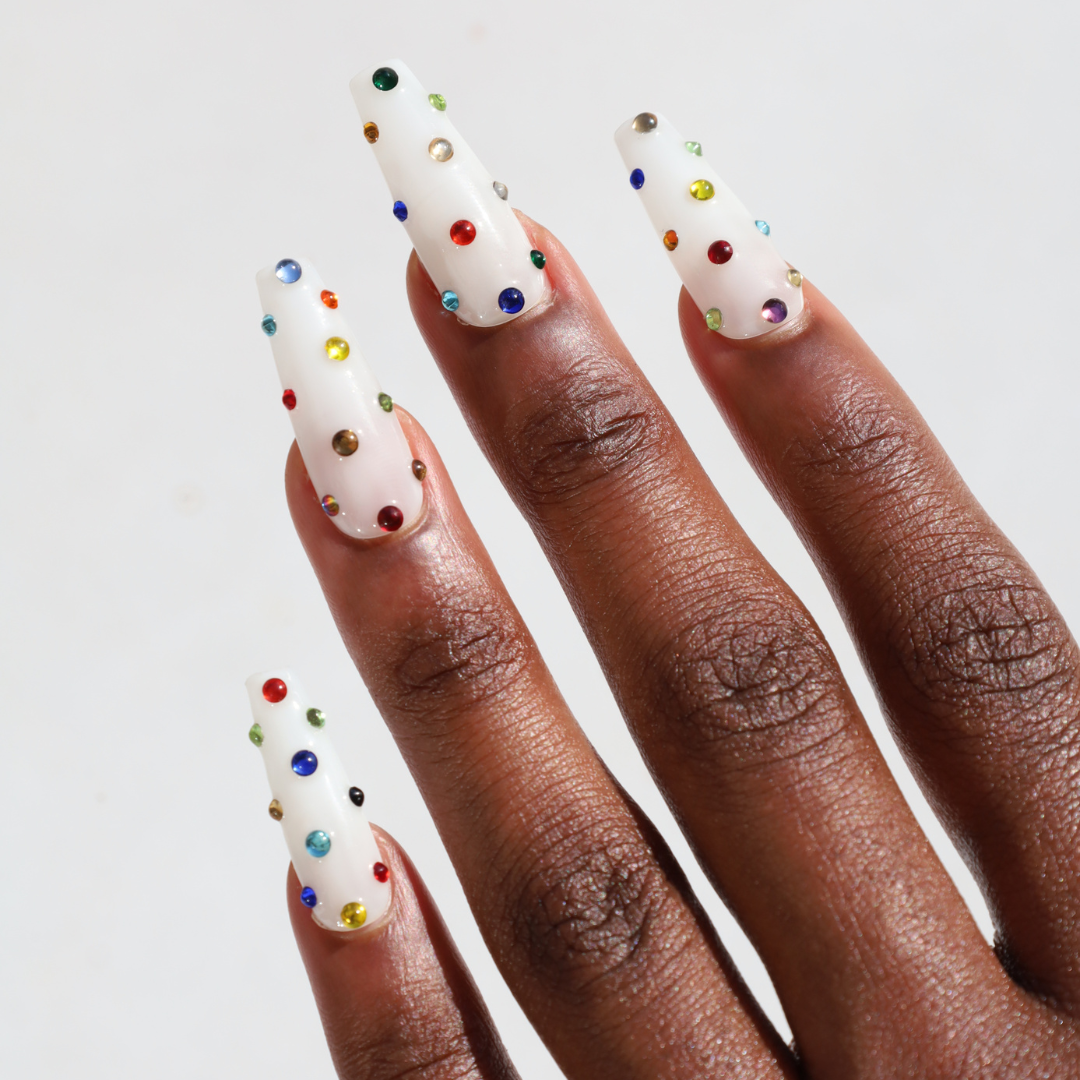 Model with lng almond press on nails with white, hot pink, blue, and orange detailing