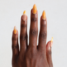 Dark skinned hand with Orange Chrome Moderne Nails